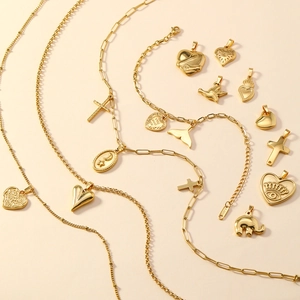 Macro shot of stainless steel gold charms featuring heart, cross, and celestial designs