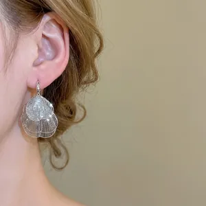 Boucles d'oreilles pétales de fleurs argentées au design superposé sur mannequin