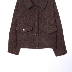 Veste en sherpa marron foncé avec col à revers et poches à rabat sur fond blanc