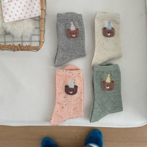 Flat lay of colorful crew socks with bear embroidery and rainbow speckle texture