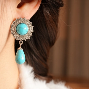 Close-up of vintage silver earring with turquoise stone and sparkling rhinestones