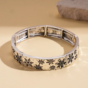 Gros plan du bracelet argenté avec gravure de flocon de neige et liens élastiques segmentés