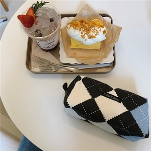 Detail of checkered knit pencil case with zipper and black merciparis label on white table