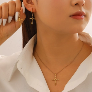 Minimalist gold hollow cross necklace and hoop earring set worn by a woman