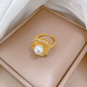 Macro detail of gold flower ring with center pearl and micro-pave crystals on the petals