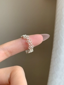 Detailed view of an open floral silver ring with hollow flower patterns on finger