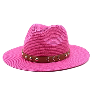Close-up of rose red straw hat featuring faux leather band and metallic rivets decoration