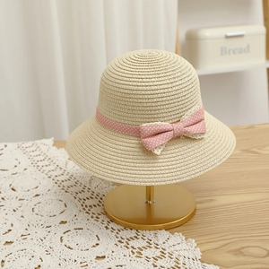 Detail of straw sun hat with pink polka dot ribbon and lace bow on a metal stand