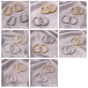 Detail view of various gold and silver hoop earrings on elegant silk fabric background