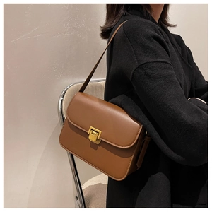 Dettaglio della borsa a tracolla in pelle marrone con elegante fibbia dorata quadrata