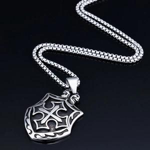 Detailed view of vintage silver cross shield pendant with skull and steel box chain