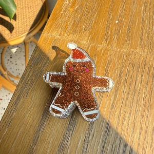 Macro detail of gingerbread man hair claw clip made of brown glitter acrylic on wood