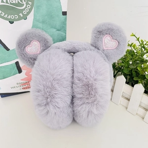 Detail of plush grey earmuffs featuring pink sequin heart patches and soft texture