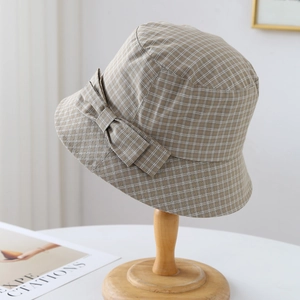 Détail d'un chapeau cloche à carreaux avec nœud décoratif sur support en bois