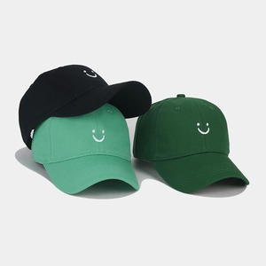 Stack of embroidered smiley face baseball caps in black, mint green, and dark green