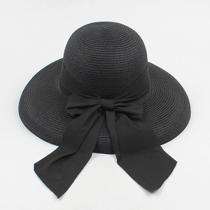Detailed close-up of a black straw sun hat with a large satin bow and woven texture