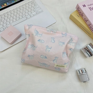 Close-up of pink toiletry bag with blue cat print, featuring a brand label and soft fabric