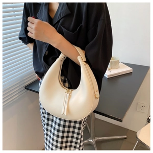 Detail of a cream hobo shoulder bag featuring golden zippers and stylish long leather tassels