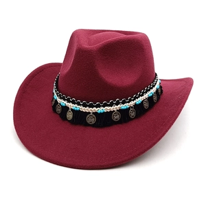 Détail d'un chapeau cowboy bordeaux avec perles ethniques, franges et pendentif en métal
