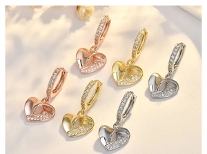 Close-up of heart earrings in gold, silver, and rose gold with zircon crystal details