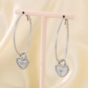 Detailed view of silver hoop earrings featuring pearly heart pendants on a pink stand