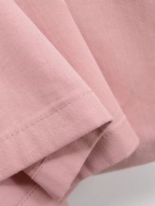 Détail de la robe rose montrant la texture du tissu sergé et la finition des coutures