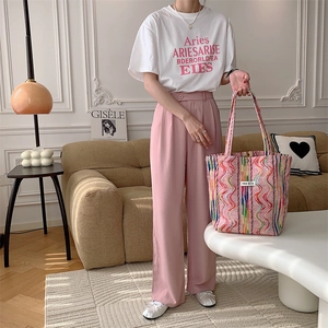 Femme avec un sac cabas en maille rayée arc-en-ciel et un pantalon rose