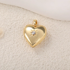 Detailansicht eines goldenen Herzanhängers mit eingefasstem Sterndiamant auf Beige