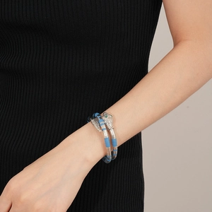 Detailed close-up of a silver snake bracelet with blue accents and green crystal eyes