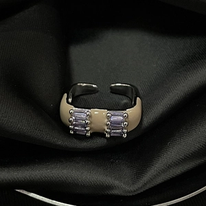 Detailed macro view of an adjustable silver ring with beige enamel and purple gemstones