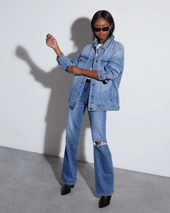 Detail of blue washed denim jacket with drop shoulders and distressed high-waist jeans