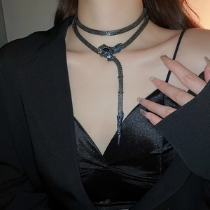 Macro detail of dark gunmetal snake necklace with scale texture and blue accents