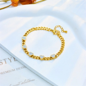 Elegant gold Cuban chain bracelet featuring five white rhinestone heart charms on a tray