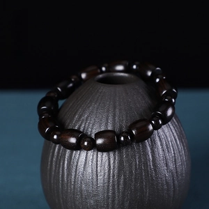 Dettaglio del bracciale in legno nero africano con grani a botte su vaso di ceramica