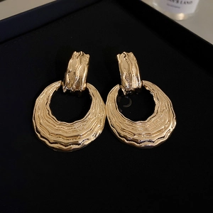 Detailed view of golden metal earrings featuring irregular water ripple textures