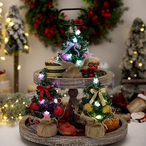 Mini lighted Christmas trees on a wooden tray with festive LED lights and ornaments