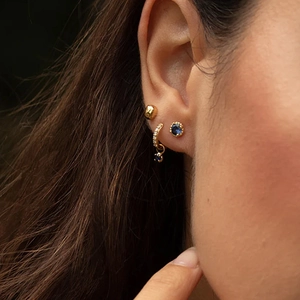 Close-up of S925 silver gold-plated hoop earrings with sparkling blue sapphire pendants