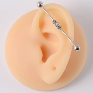 Detailed macro view of silver industrial barbell earring with clear crystal on ear model