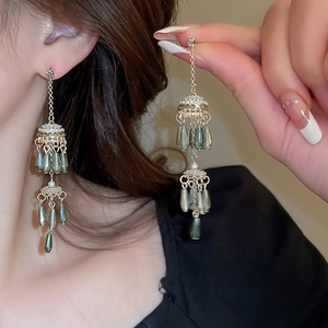 Detail of elegant gold tassel earrings with teardrop pearls and rhinestones on model