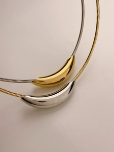 Detail of minimalist dual-tone titanium necklaces with curved tube pendants and snake chains