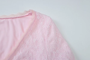 Détail de l'encolure en V en dentelle rose avec broderies florales délicates sur la manche
