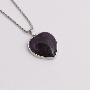 Macro shot of a heart-shaped purple amethyst crystal pendant on a silver rope chain