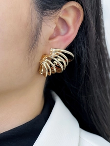 Detail of golden multilayer ring spiral earrings showing the polished alloy metal texture