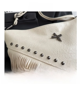 Detailed close-up of white fringe bag featuring metal rivets and cross emblem hardware
