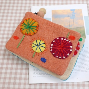 Handmade wool felt coin purse with dandelion embroidery on a warm vintage background