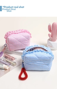 Detail of pink and blue quilted plaid cosmetic bags with ruffle edges and fuzzy zipper pulls
