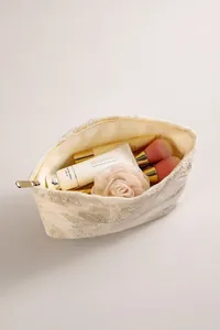 Vue de dessus d'une trousse à maquillage en lin brodé avec motifs floraux et rangement