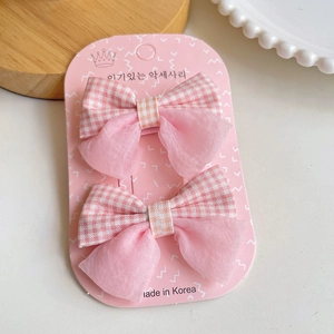 Détail de barrettes à nœuds en tulle rose et tissu à carreaux sur carte cadeau