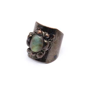 Detail of vintage bronze ring with oval green gemstone and floral embossed texture