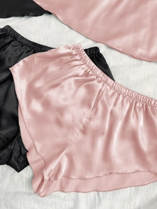 Détail du short de nuit en satin avec taille élastique et bords ondulés en rose et noir